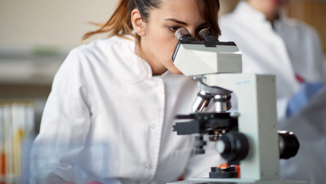 Investigadora científica analizando resultados con un microscopio